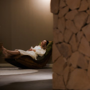 Vrouw in badjas ligt op relax stoel in de rustruimte met mergelstenen bij Thermae 2000.